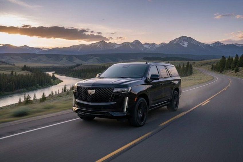 En sort SUV kører på en vej med bjerge i baggrunden. 1