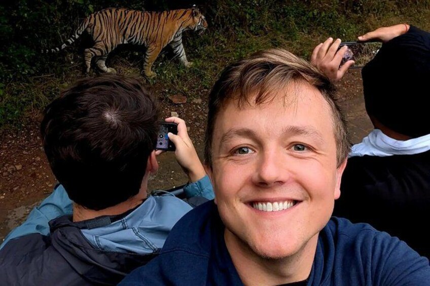 En person som tar en selfie med en tiger i bakgrunden. 1