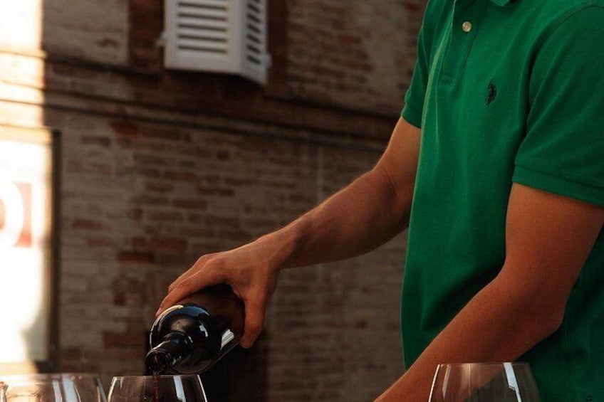 A person pouring a dark liquid into a clear glass. 2