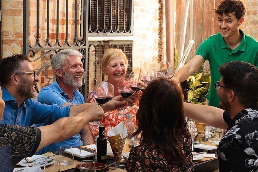 A group of people toasting with wine glasses at a table. 4