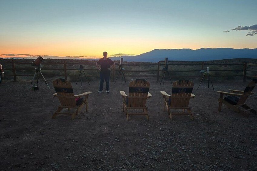 A sunset view with chairs and tripods on a dirt ground. 2
