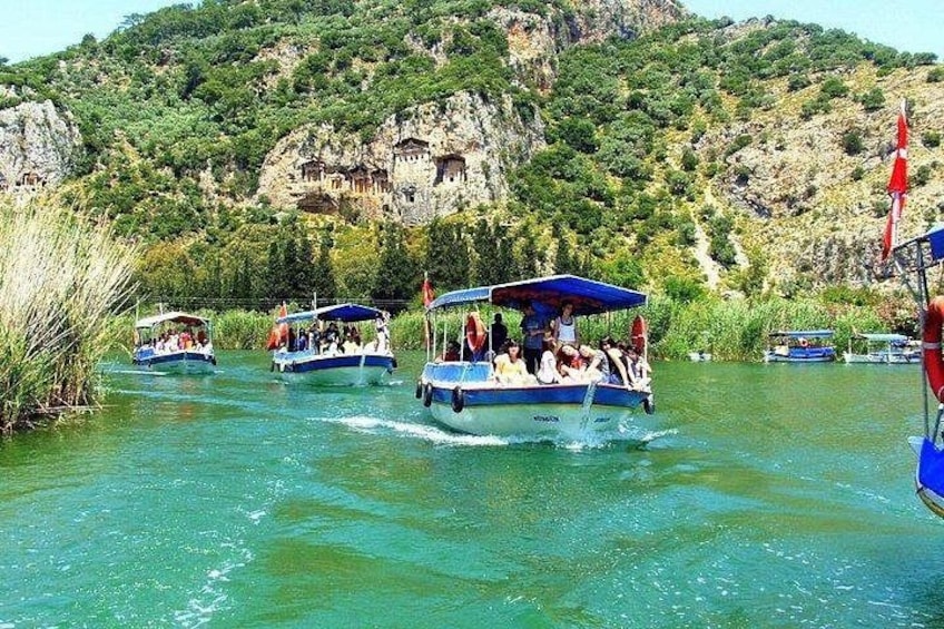 A group of boats on a river with passengers, surrounded by greenery and rocky cliffs. 1