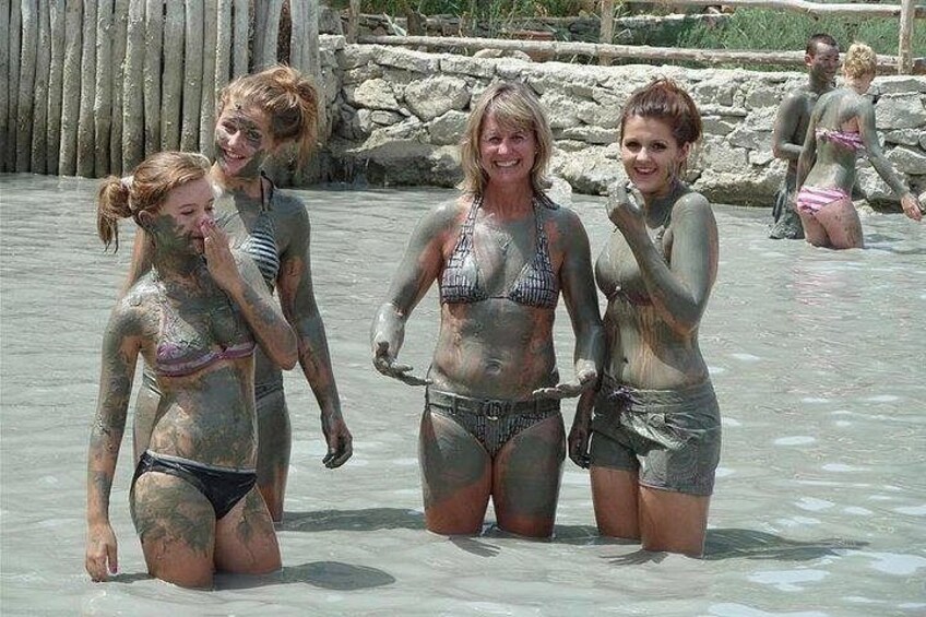 People in a natural water setting, some covered in mud. 4
