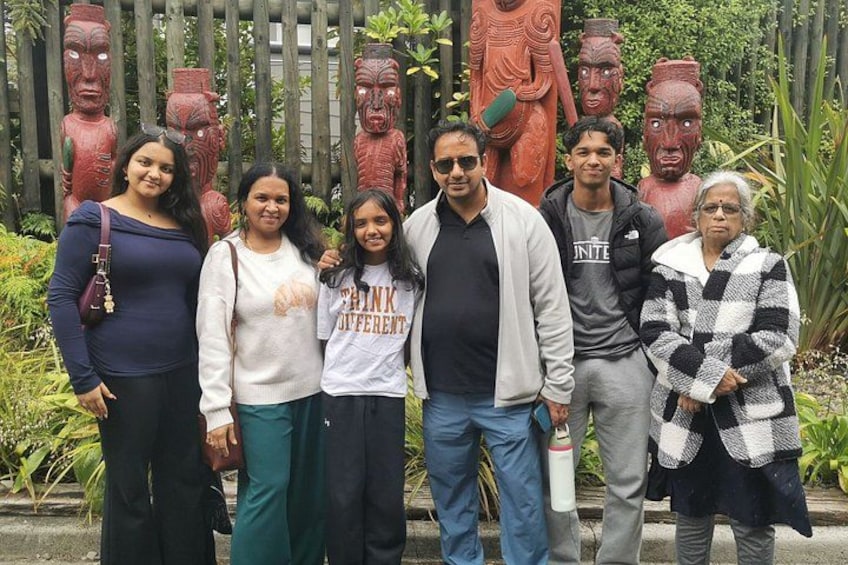 Eine Gruppe von Personen posiert vor einem Holzzaun mit roten Statuen. 2