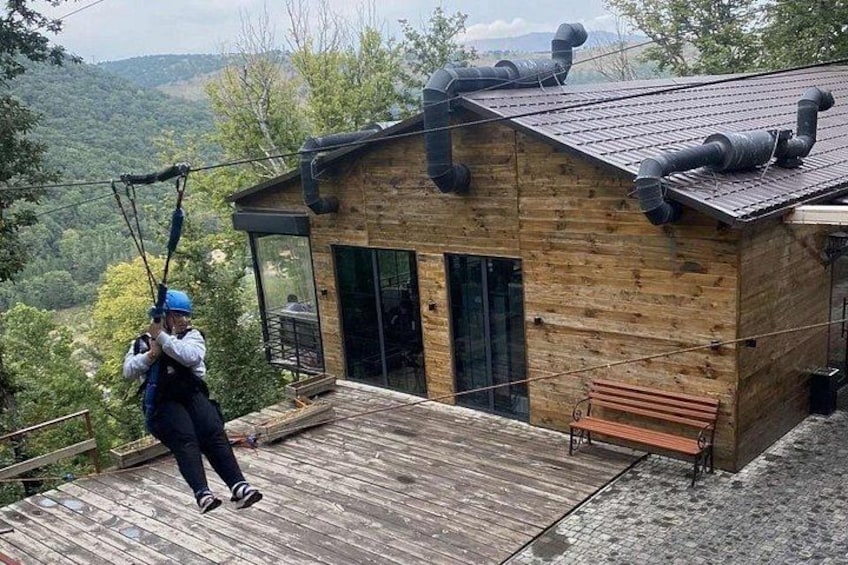 Een houten hut met een metalen dak, een houten terras en een zipline. 5