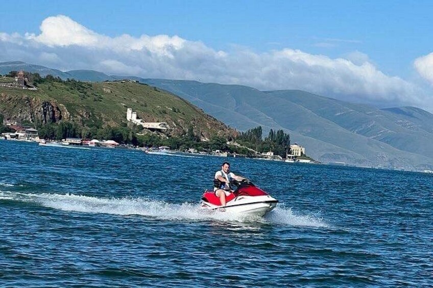 Iemand gaat jetskiën op een meer, met een bergachtig landschap op de achtergrond. 3