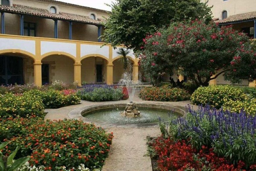 A courtyard with a fountain, surrounded by colorful flowers and a building with arches. 2