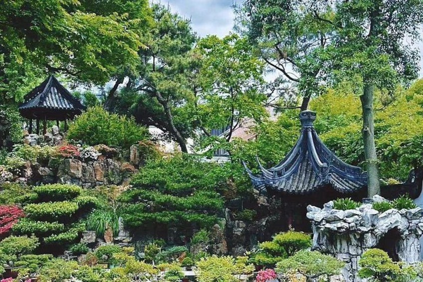 A traditional garden with rock formations, a pagoda, and various shrubs. 1