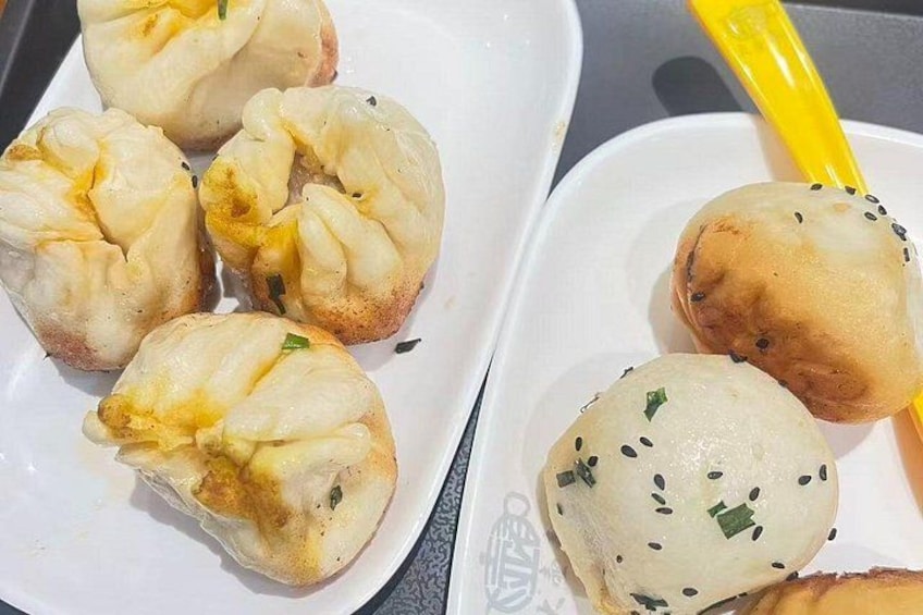 A plate of steamed buns with sesame seeds. 5