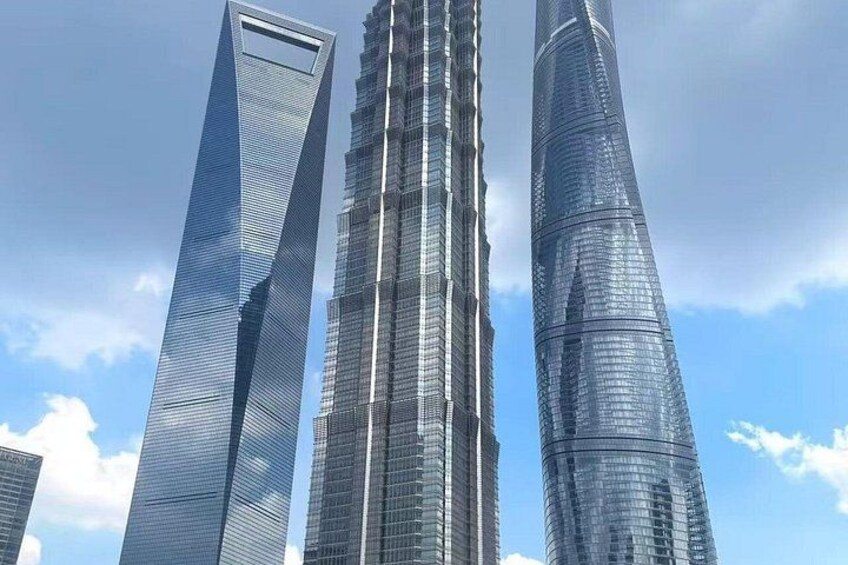 Three tall skyscrapers with reflective glass facades, set against a partly cloudy sky. 2
