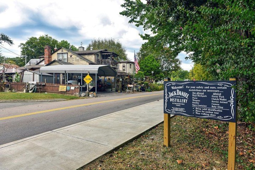 A distillery sign with a list of prohibited items and a caution sign for a curve ahead. 2