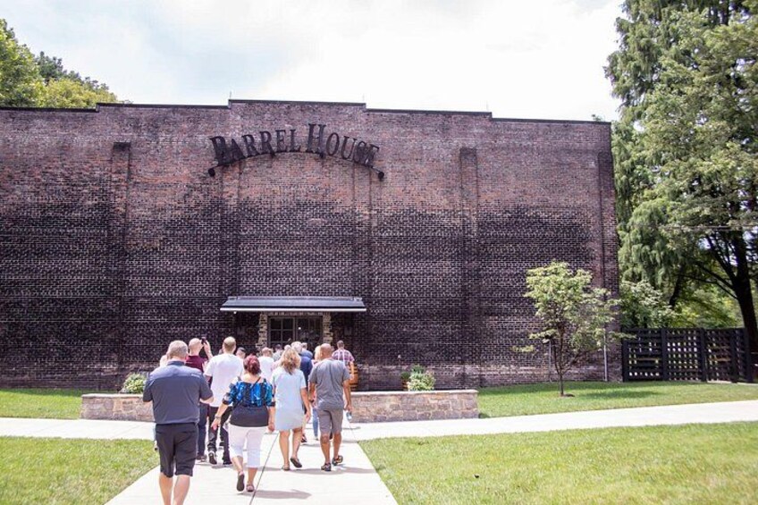 A brick building with the inscription 'Barrel House' and a group of people walking in front. 1