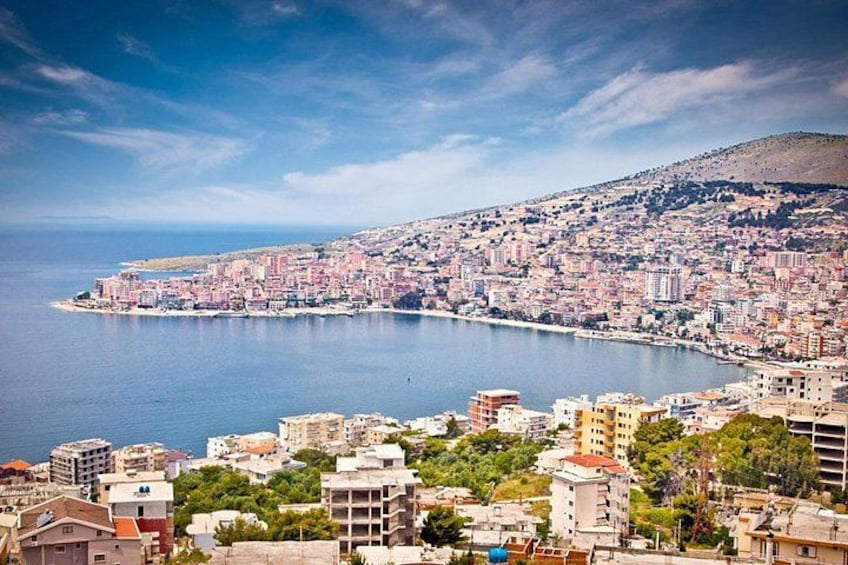 Un paysage urbain côtier avec une vaste étendue d’eau, des bâtiments urbains denses et un arrière-plan vallonné. 3