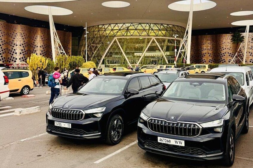 Two black BMW cars parked in front of a modern building with a circular glass facade. 3