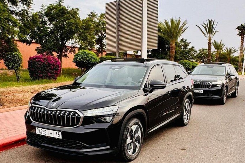 A black SUV parked on a street with a building and trees in the background. 5