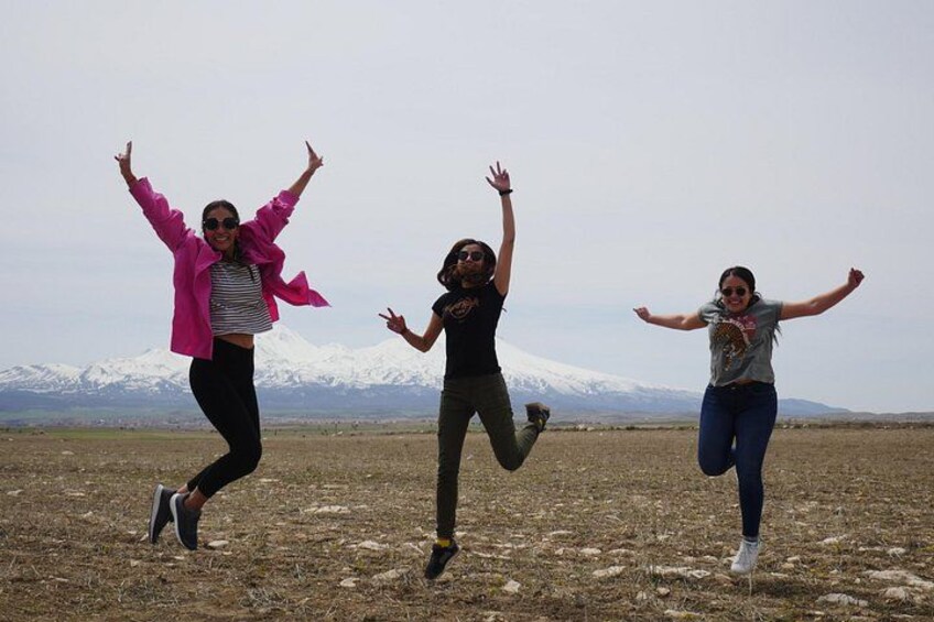 Tres personas saltando en un campo abierto con una montaña al fondo. 3