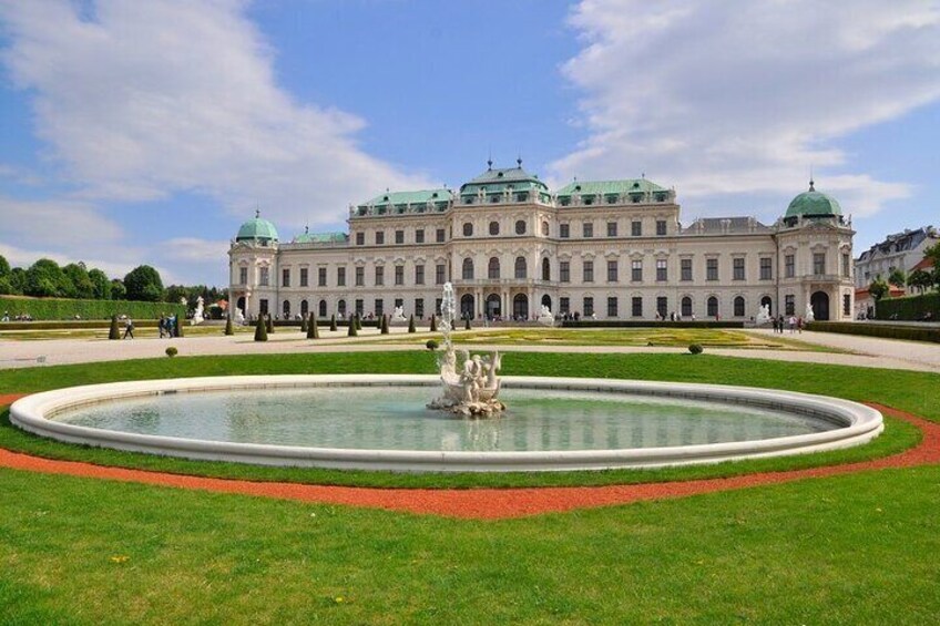 A large historic building with a central fountain and manicured gardens. 5