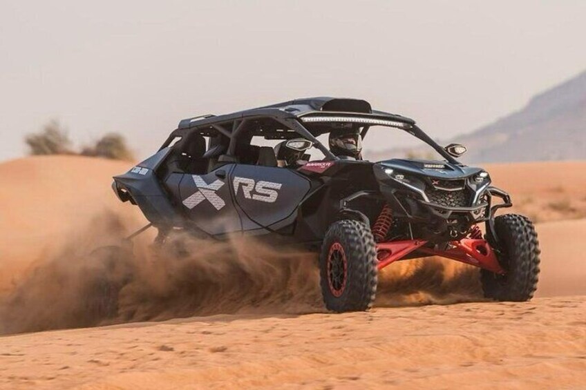 Un vehículo todoterreno negro y rojo con la marca 'XRS' en la carrocería, circulando por un desierto levantando arena. 5