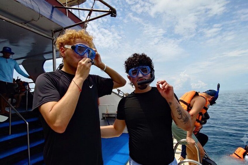 Two people on a boat wearing diving gear, with another person in the background. 4