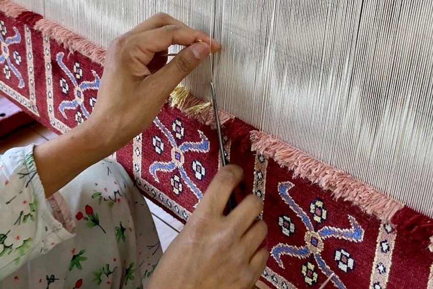 Hands weaving a patterned fabric. 4