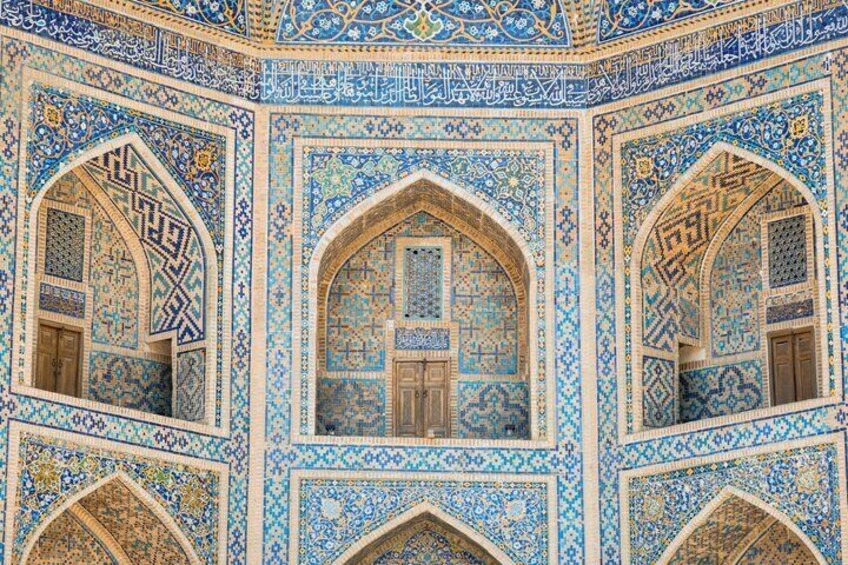 A detailed interior with blue and gold tile patterns, arched windows, and intricate geometric designs. 2