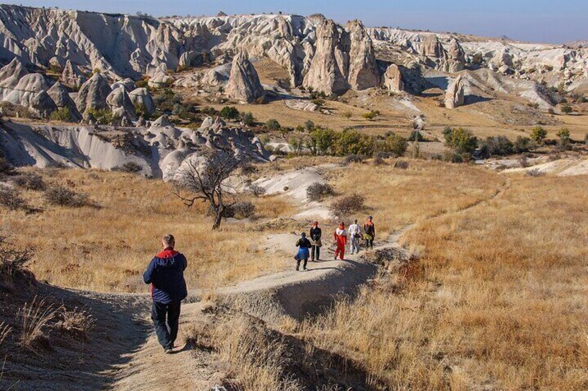 Un grupo de personas caminando por un sendero de tierra en un paisaje rocoso y seco, con vegetación escasa. 3