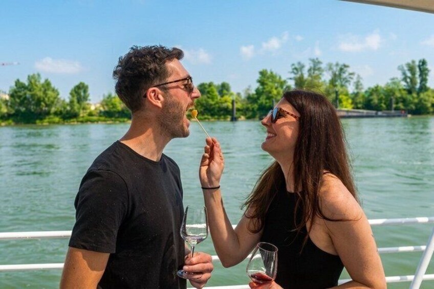 Dos personas en un bote, una sosteniendo una copa de vino y la otra una cuchara con comida. 1