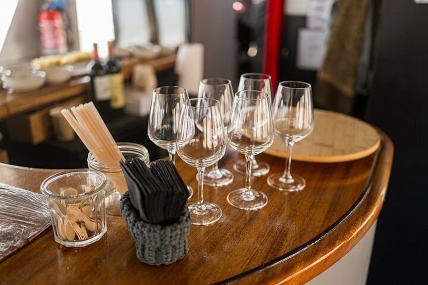 Een bar met lege wijnglazen en een servetdispenser op een houten toog. 2