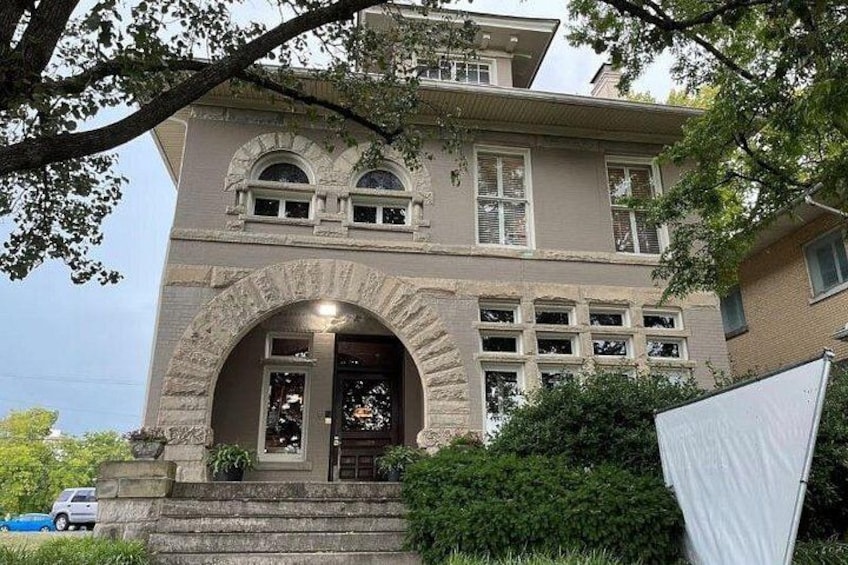 A two-story house with a stone archway entrance, a front porch, and a garage. 2