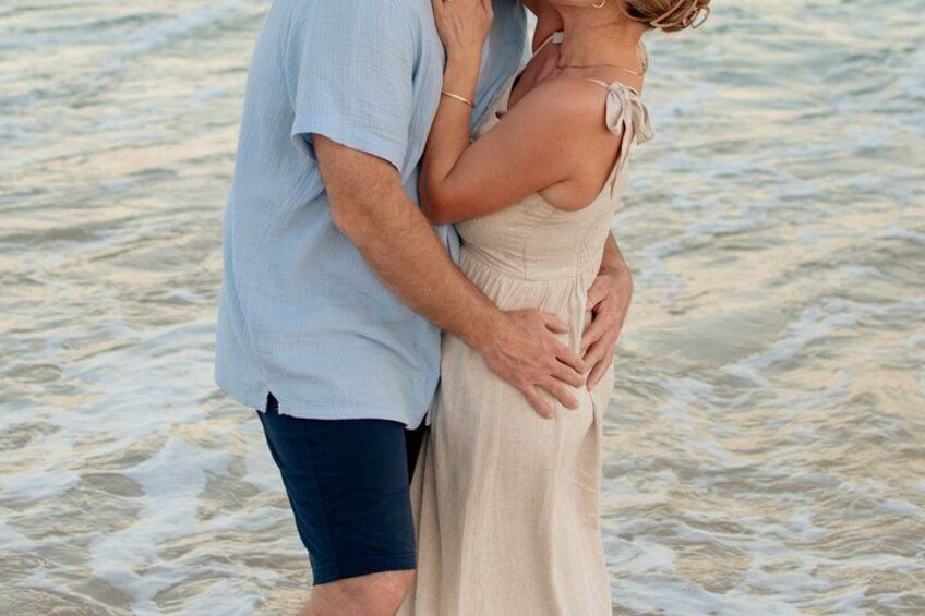 A couple embracing on a beach with waves in the background. 5
