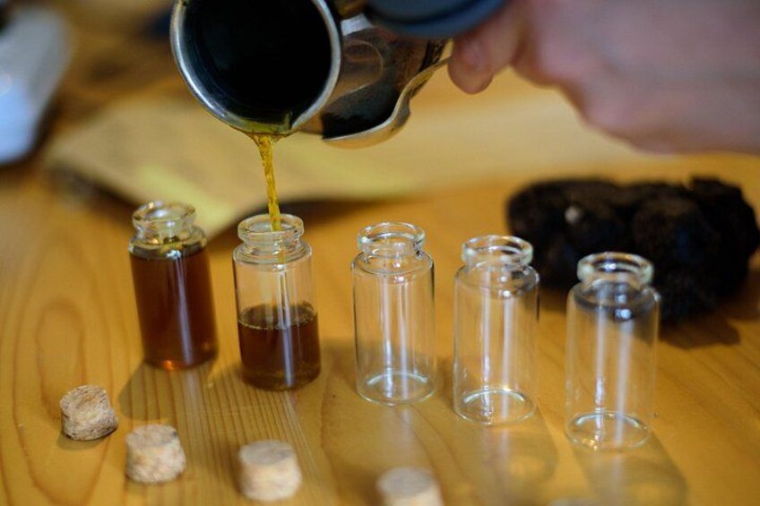 Iemand giet een vloeistof in verschillende kleine glazen flesjes. 5