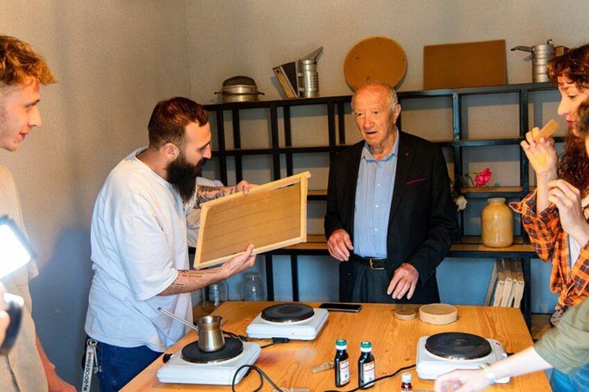 Een groep mensen rond een tafel met een houten plank, een weegschaal en flessen. 2