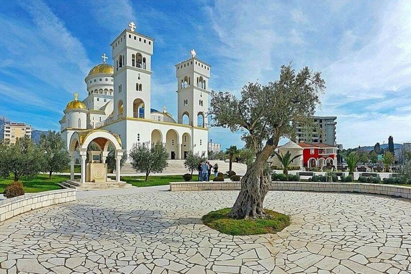 A church with domes and a courtyard with a tree. 2
