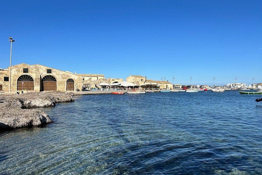 En kystby med historiske bygninger, blå himmel og både i havnen. 2
