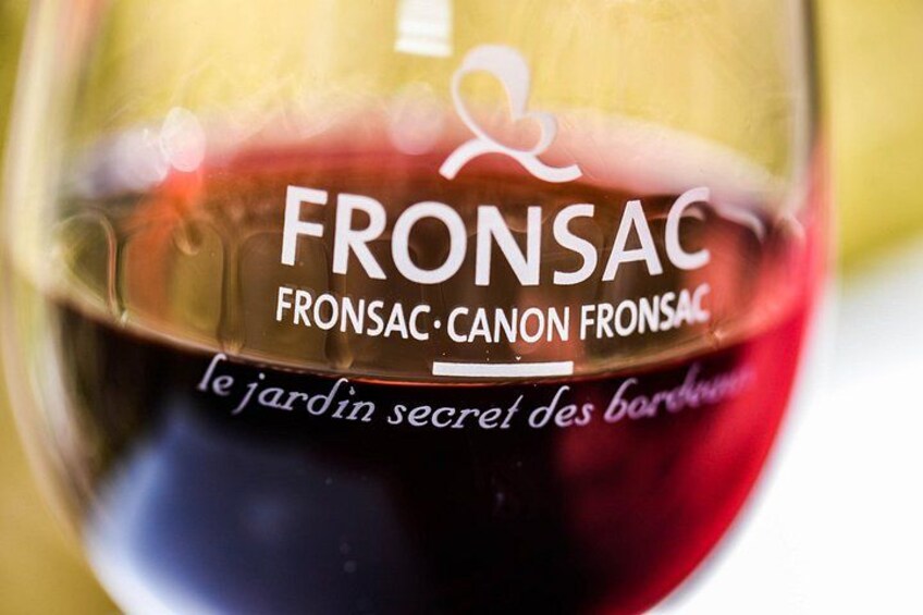 A wine glass with the text 'FRONSAC' and 'le jardin secret des barbes' on it. 1