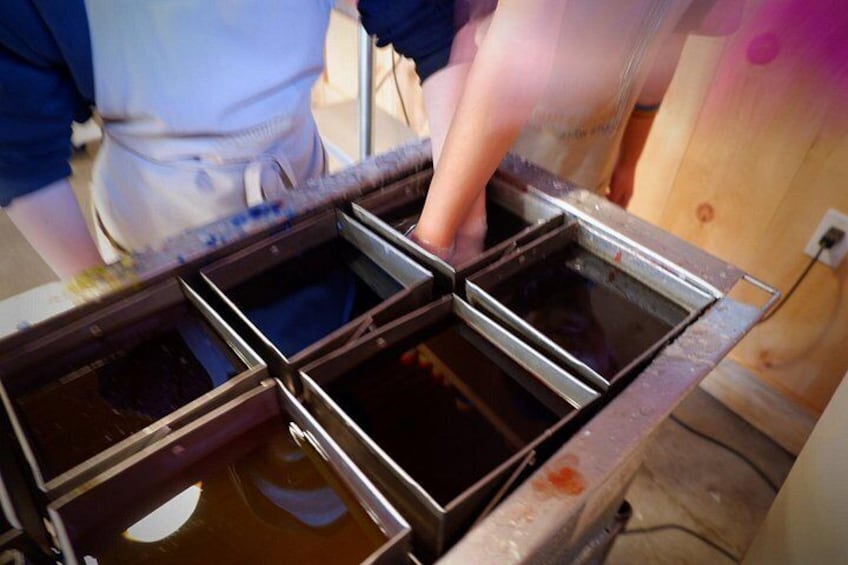 A person pouring liquid into a metal container. 3