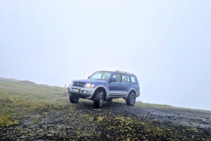Un SUV azul estacionado en una colina cubierta de césped bajo un cielo nublado. 2