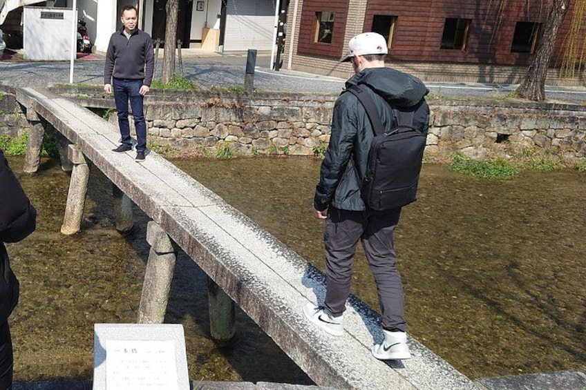 A stone bridge over a body of water with people standing on it. 2