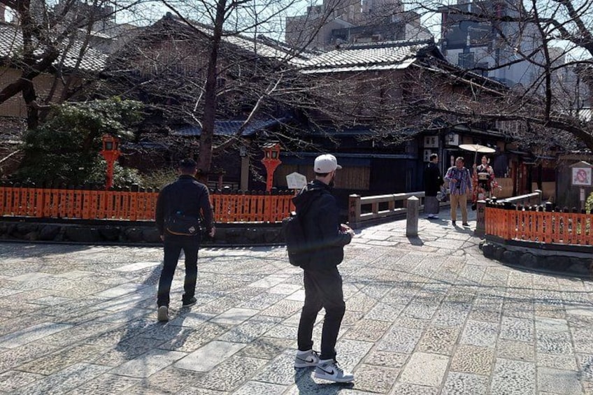 A traditional Japanese temple with a tiled courtyard, a stone lantern, and a red fence. 4