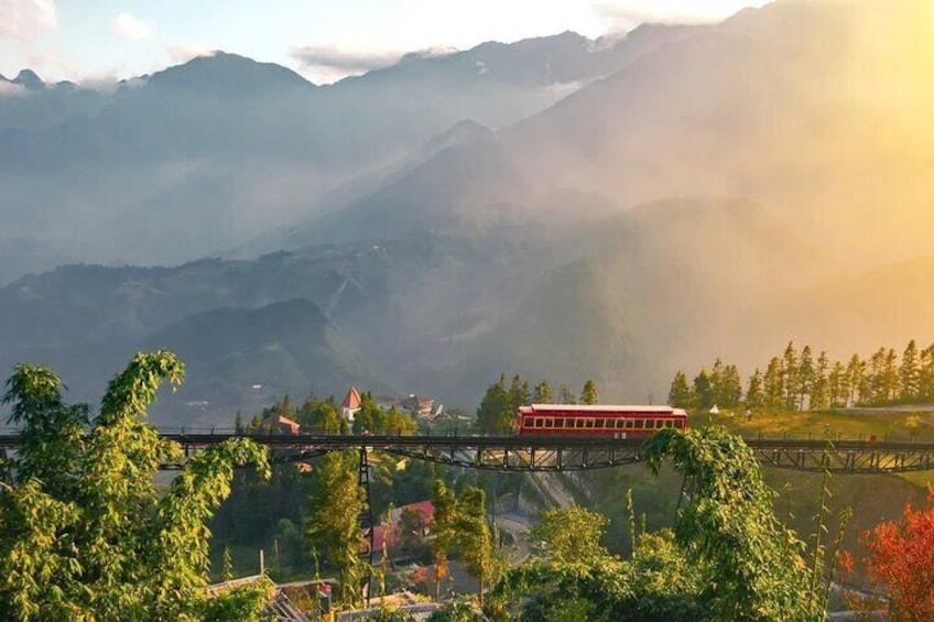 A red train on a bridge with mountains in the background. 5
