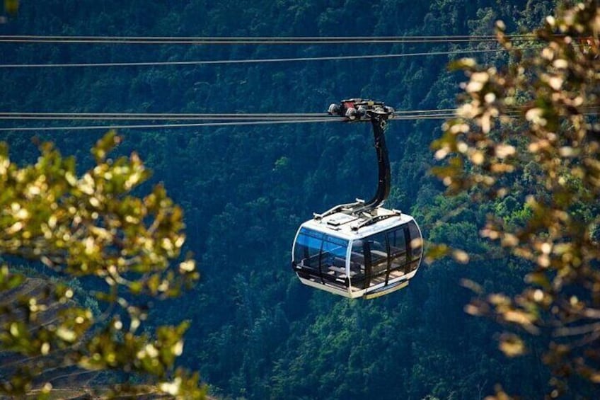 A cable car suspended over a forested mountain area. 4