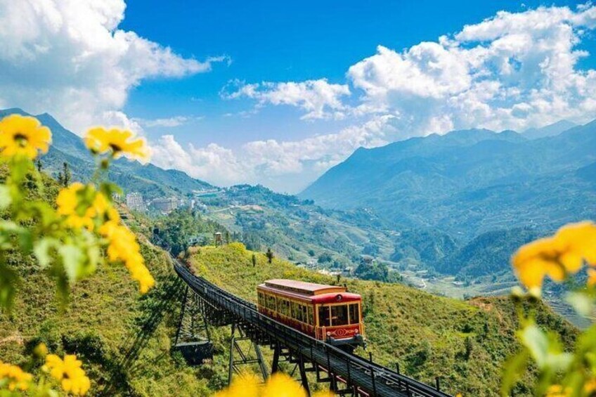 A red cable car on a mountain track with lush greenery and distant mountains. 1
