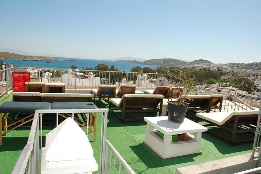 A rooftop terrace with outdoor seating, a potted plant, and a view of the sea and hills. 5