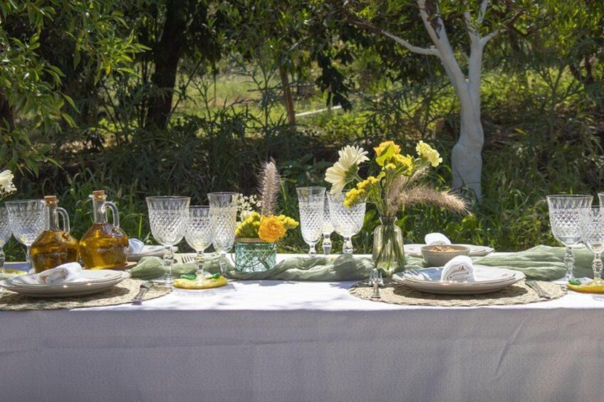 Un tavolo apparecchiato all'aperto con bicchieri, piatti e fiori. 3