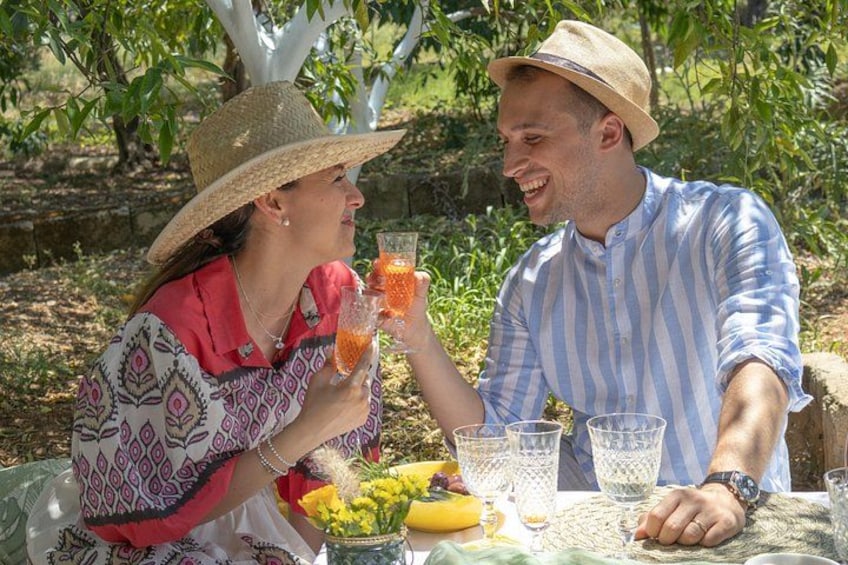 Deux personnes sont assises à une table à l’extérieur, devant des boissons et des fruits. 1