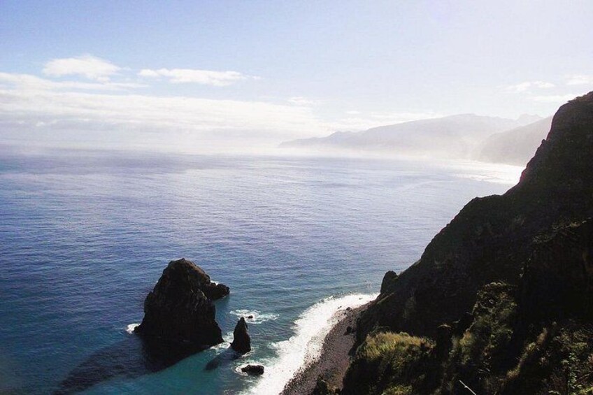 A coastal landscape with rocky cliffs, a beach, and the ocean. 4