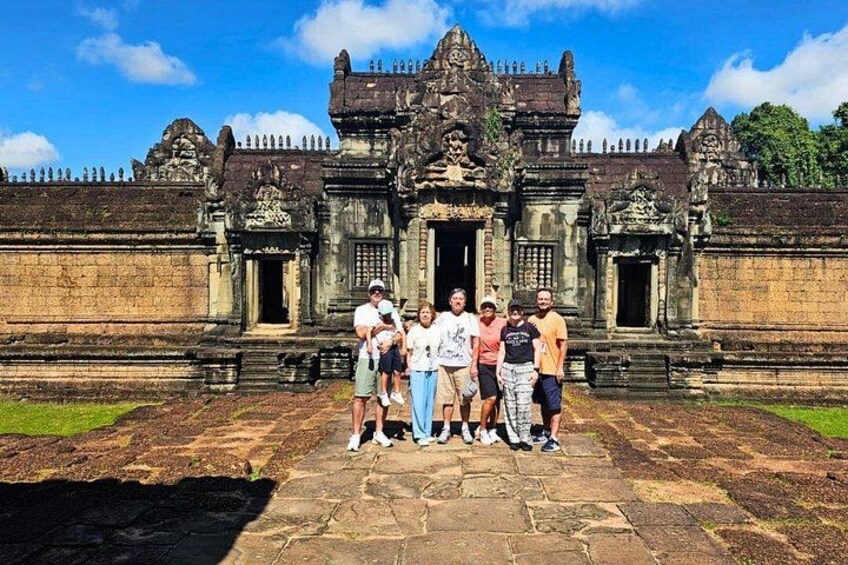 Eine Gruppe von Menschen steht vor einem antiken Tempel mit aufwendigen Schnitzereien und einem großen Eingang. 4