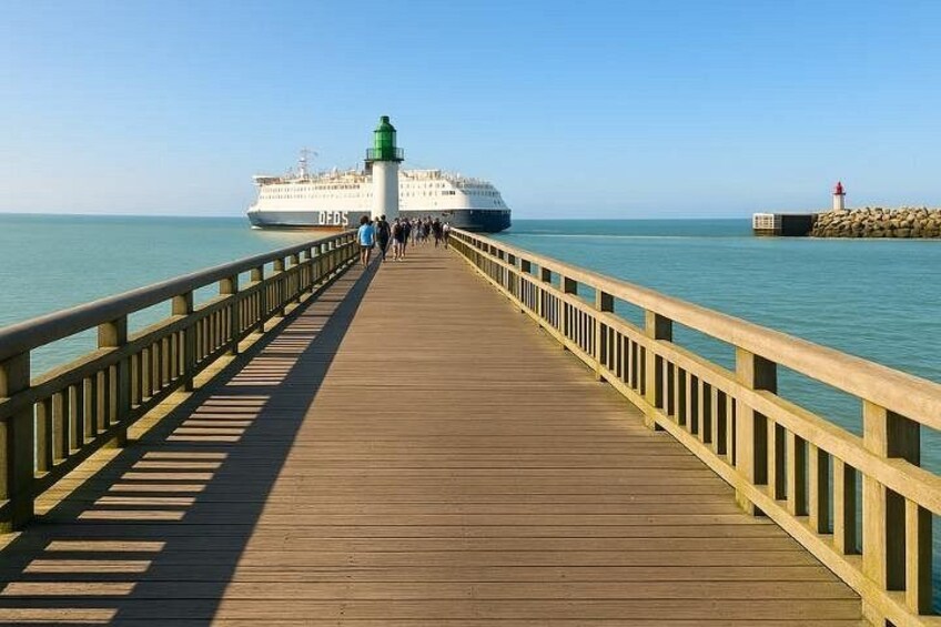 A wooden pier extending into calm waters with a cruise ship in the distance and a lighthouse on the right. 5
