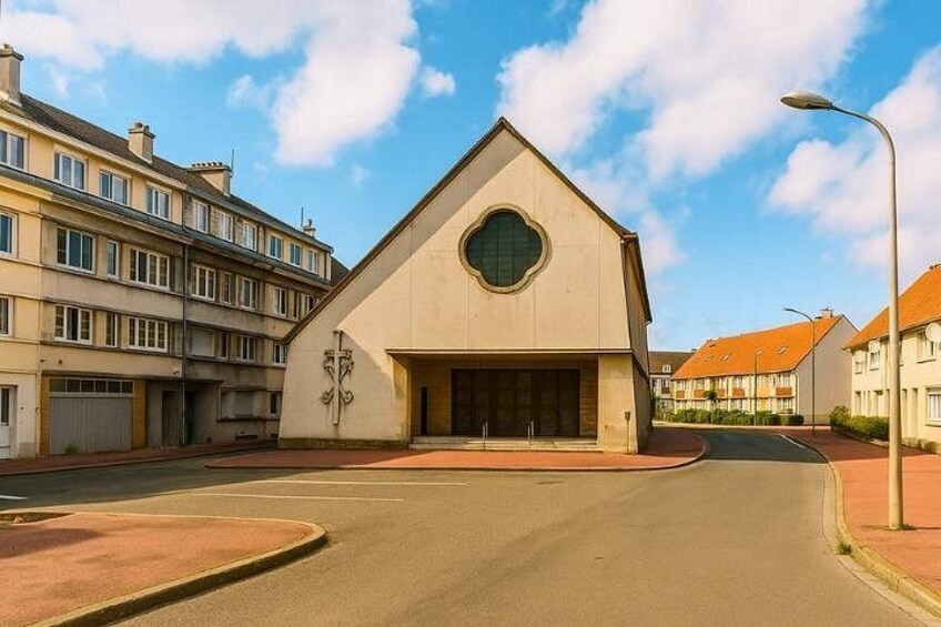 A modern building with a triangular roof and a circular window, surrounded by residential buildings. 4