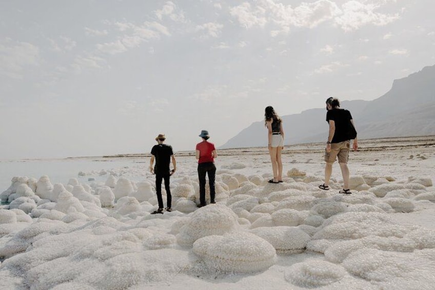 People standing on a salt flat with white salt formations and mountains in the background. 4